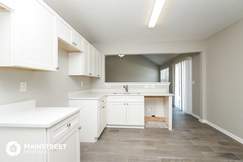a large white kitchen with white cabinets and tile floor