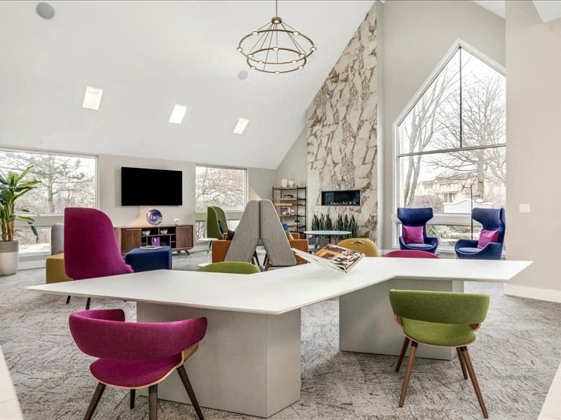 a large white table with colorful chairs in a living room