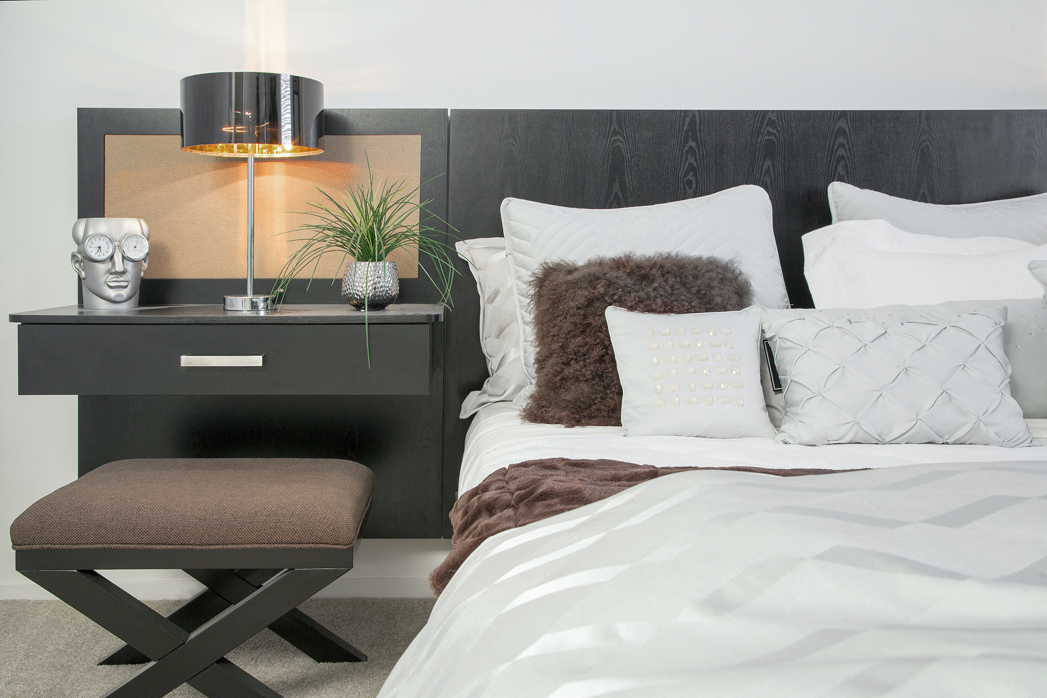 a bedroom with a bed with white sheets and pillows and a black headboard