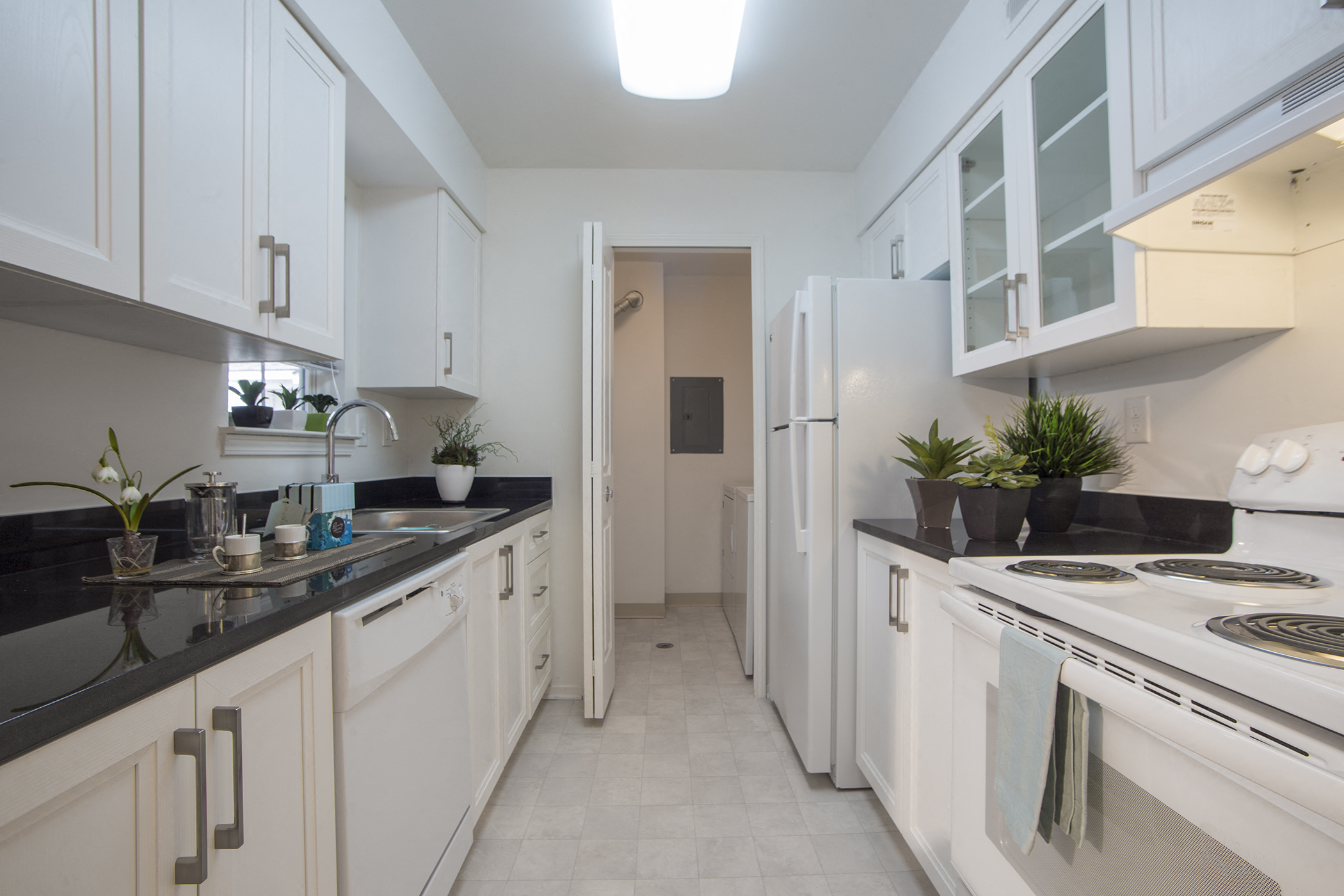a kitchen with white cabinets and black counter tops and a white stove and refrigerator