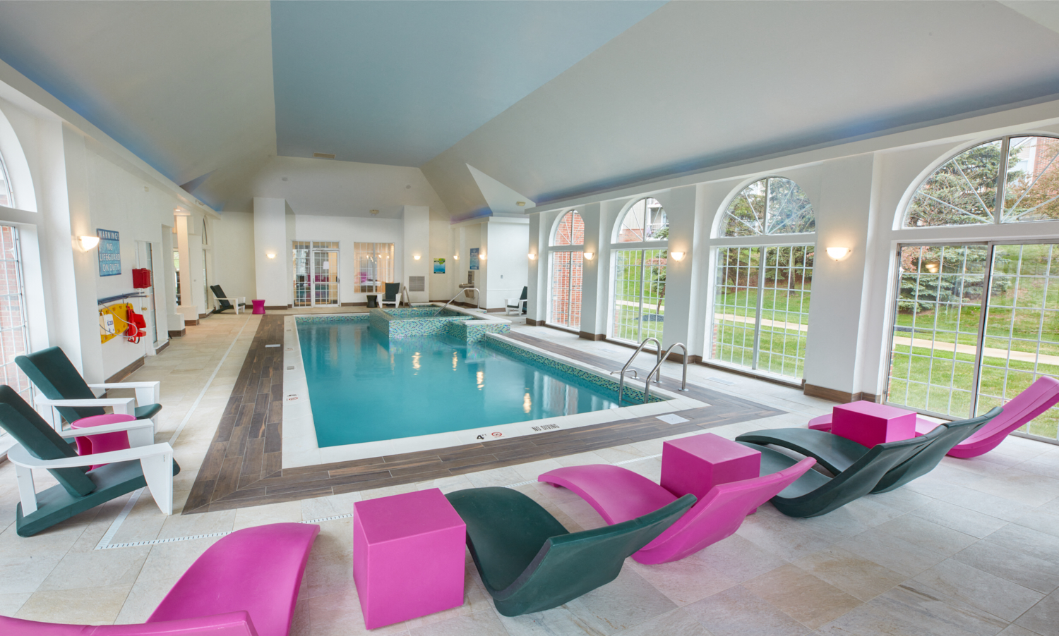 a swimming pool surrounded by chairs and large windows