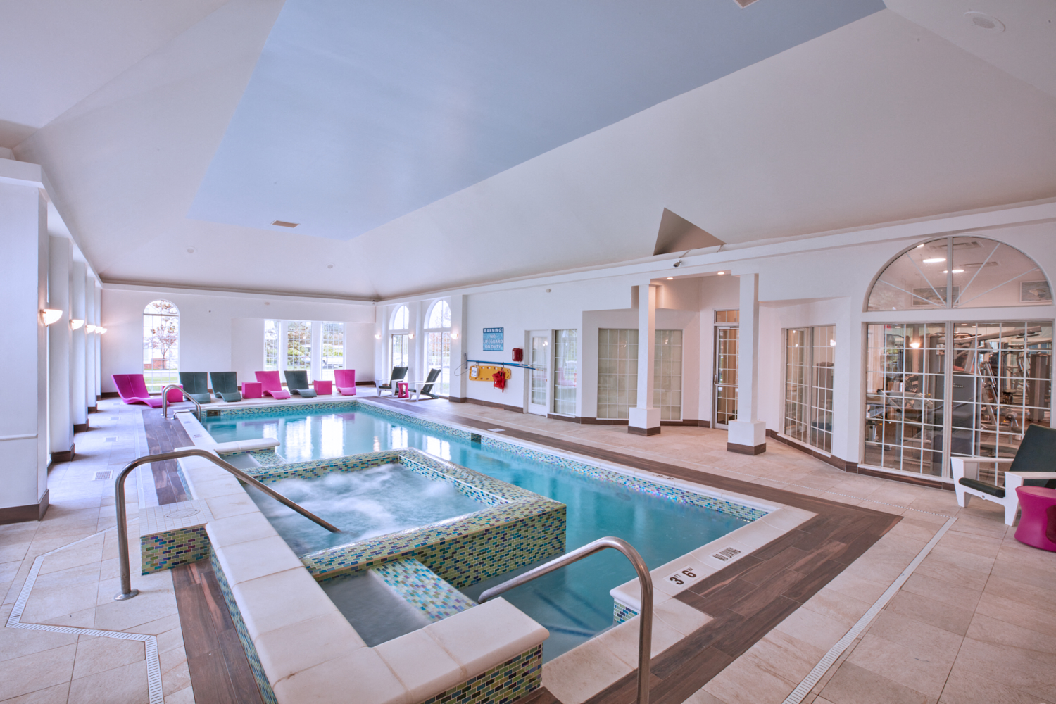 a swimming pool in the middle of a large room with stairs and chairs