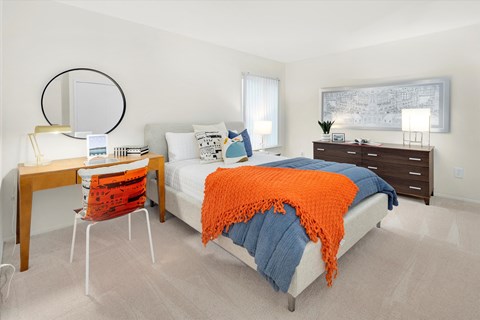 a bedroom with a bed and a desk with a mirror