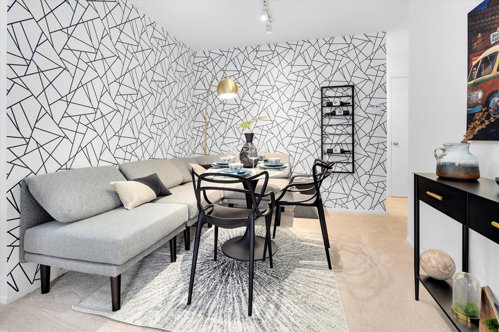 a living room with a table and a couch and a geometric wallpaper