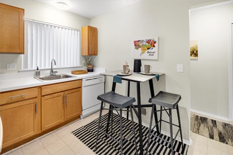a kitchen with a bar table and two stools in front of a sink