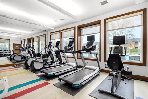 a gym with treadmills and other exercise equipment and windows