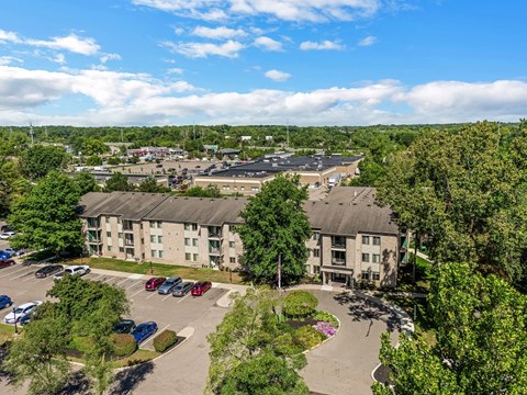 an aerial view of an apartment complex with parking lot and trees