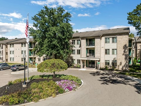 an apartment building with an flag and a tree in front of it
