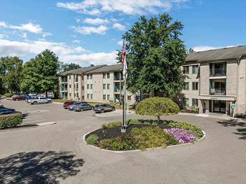 an empty parking lot in front of an apartment building with a flag