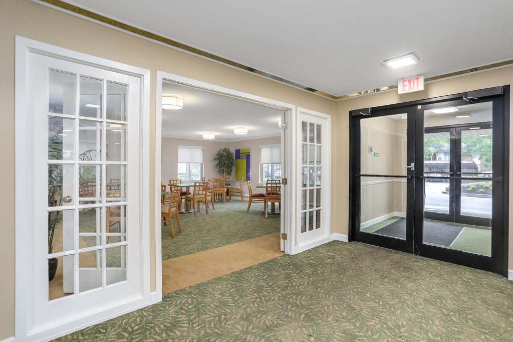 a room with doors and tables and chairs in a lobby
