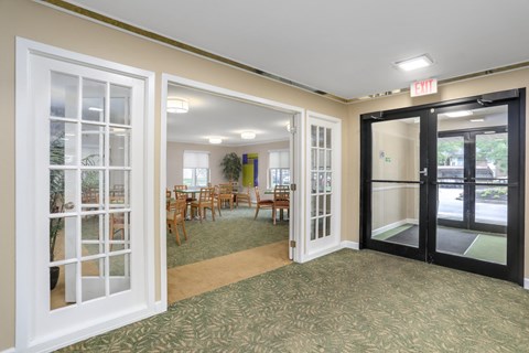 a room with doors and tables and chairs in a lobby