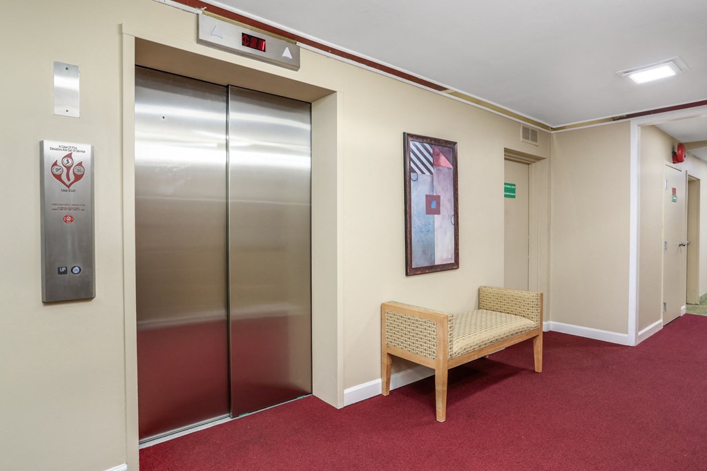 a corridor with elevators and a chair in front of a door