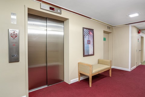 a corridor with elevators and a chair in front of a door