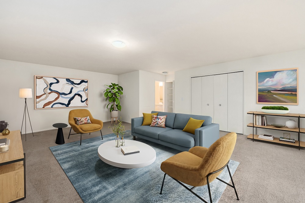 A living room with a grey couch, a yellow chair, a white coffee table, and a painting on the wall.