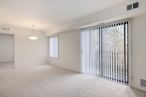 the living room of an apartment with a large window and a door to the balcony