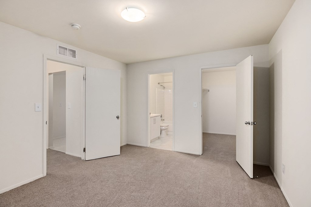 a bedroom with white walls and doors and a carpeted floor