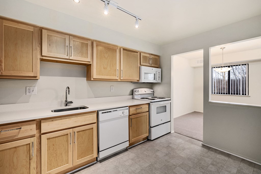 an empty kitchen with white appliances and wooden cabinets