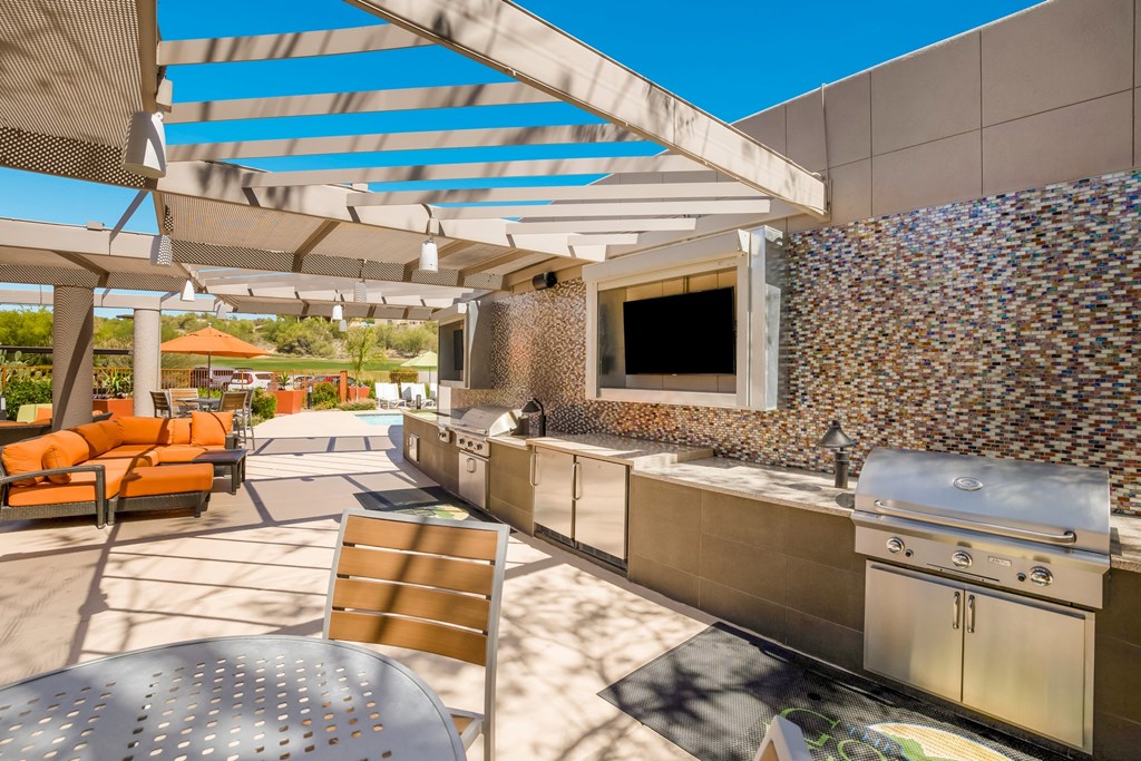 the outdoor kitchen has stainless steel appliances and a patio