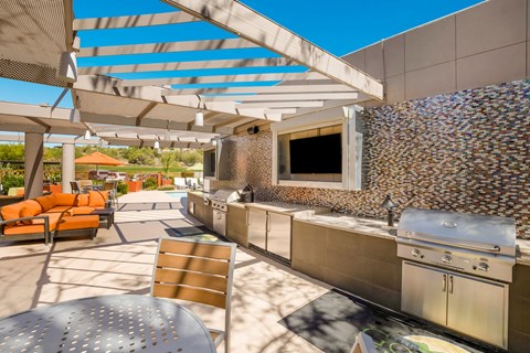 the outdoor kitchen has stainless steel appliances and a patio