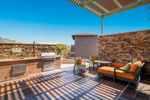 a covered patio with a grill and a table and chairs