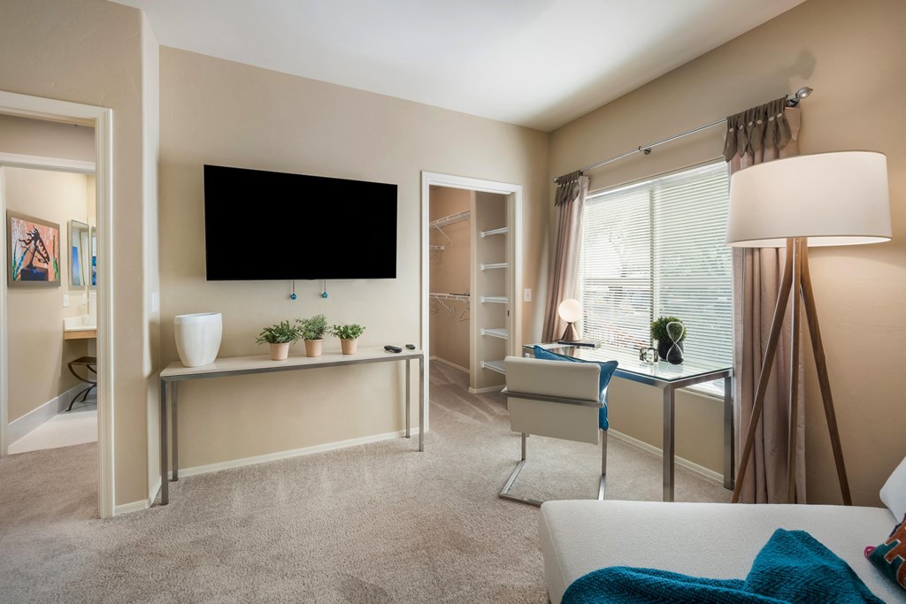 a living room with a large window and a desk with a chair