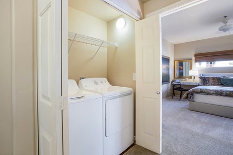 a laundry room with a washer and dryer and a bedroom with a bed