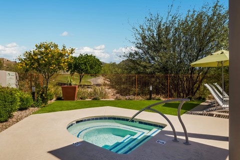 a hot tub in a backyard with a patio and a umbrella
