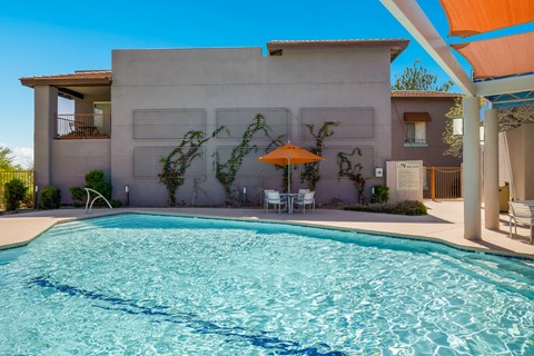 a swimming pool in front of a house with an umbrella