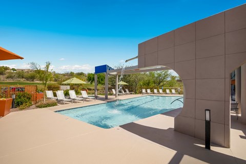 a swimming pool with chairs and a building with a blue sky