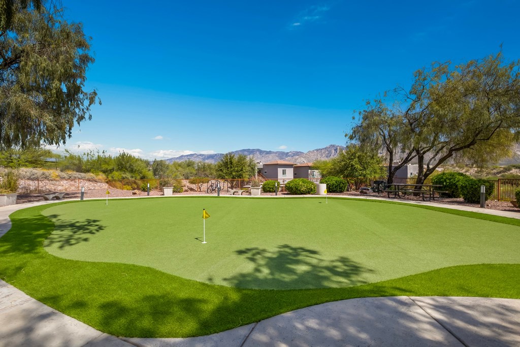 a putting green with a house in the background