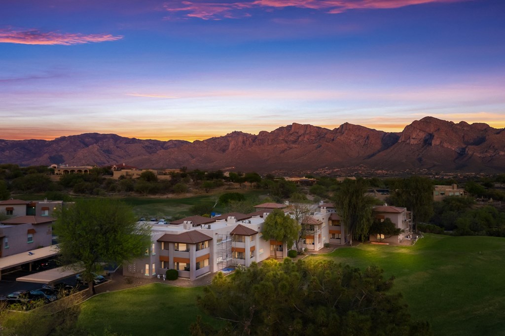 an aerial view of homes with mountains in the background at sunset