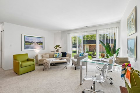 A living room with a green chair and a glass table.
