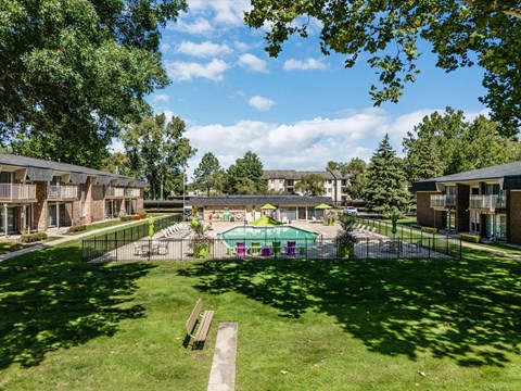 a yard with a pool and apartments in the background