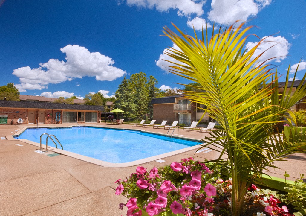 a pool with chairs around it in front of a building