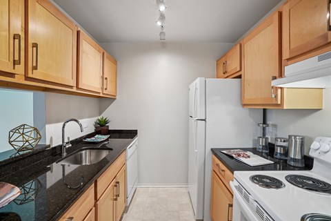 A kitchen with a white refrigerator and black countertops.
