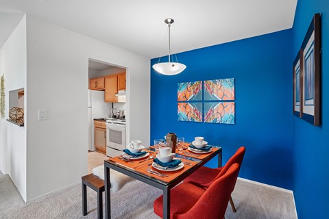 A dining room with a table set for two and a red chair.