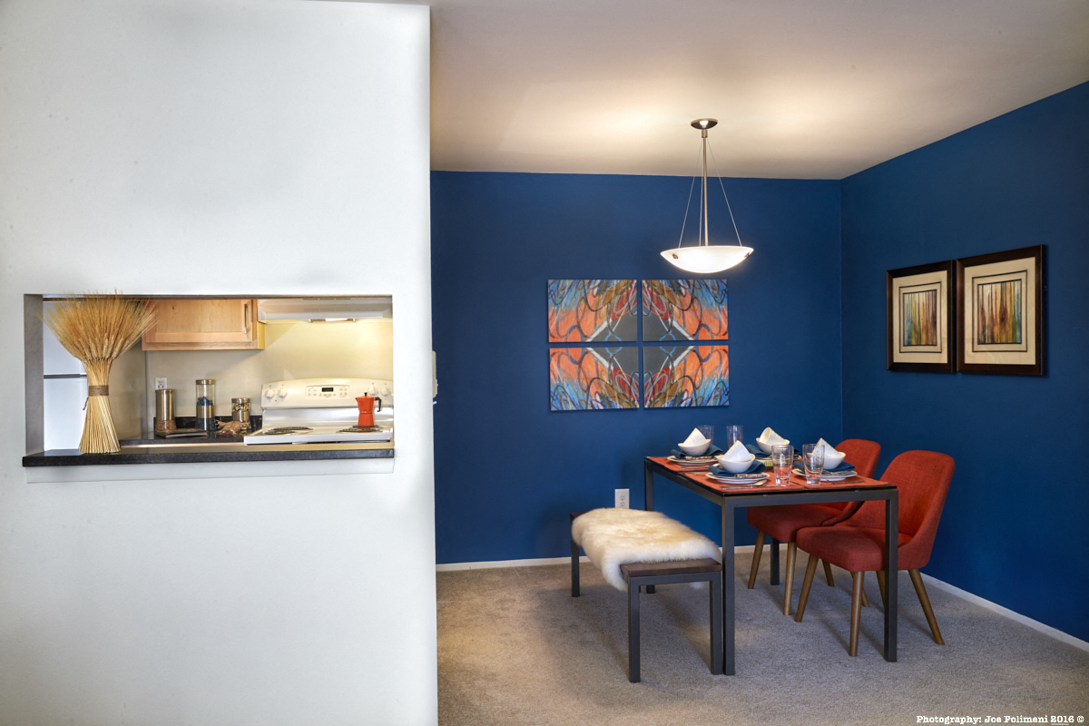 a dining room and a kitchen in a home with a blue wall