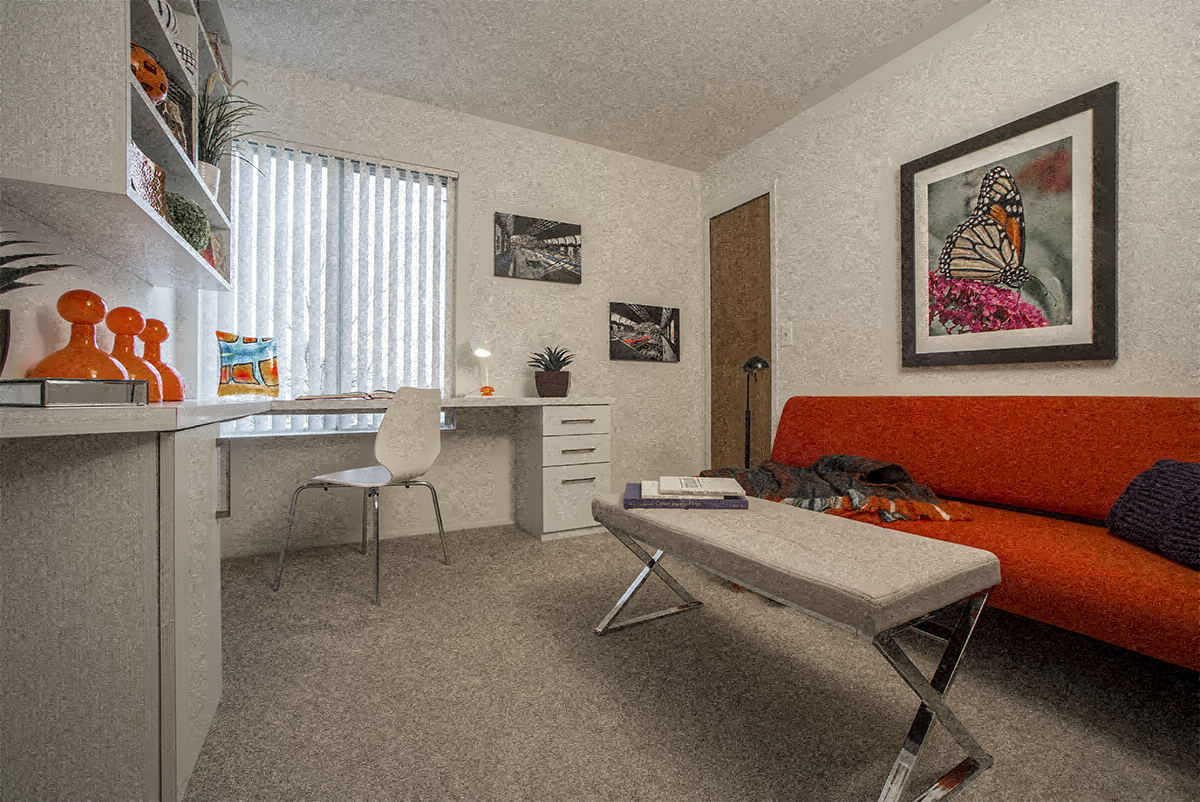 a living room with a orange couch and a desk