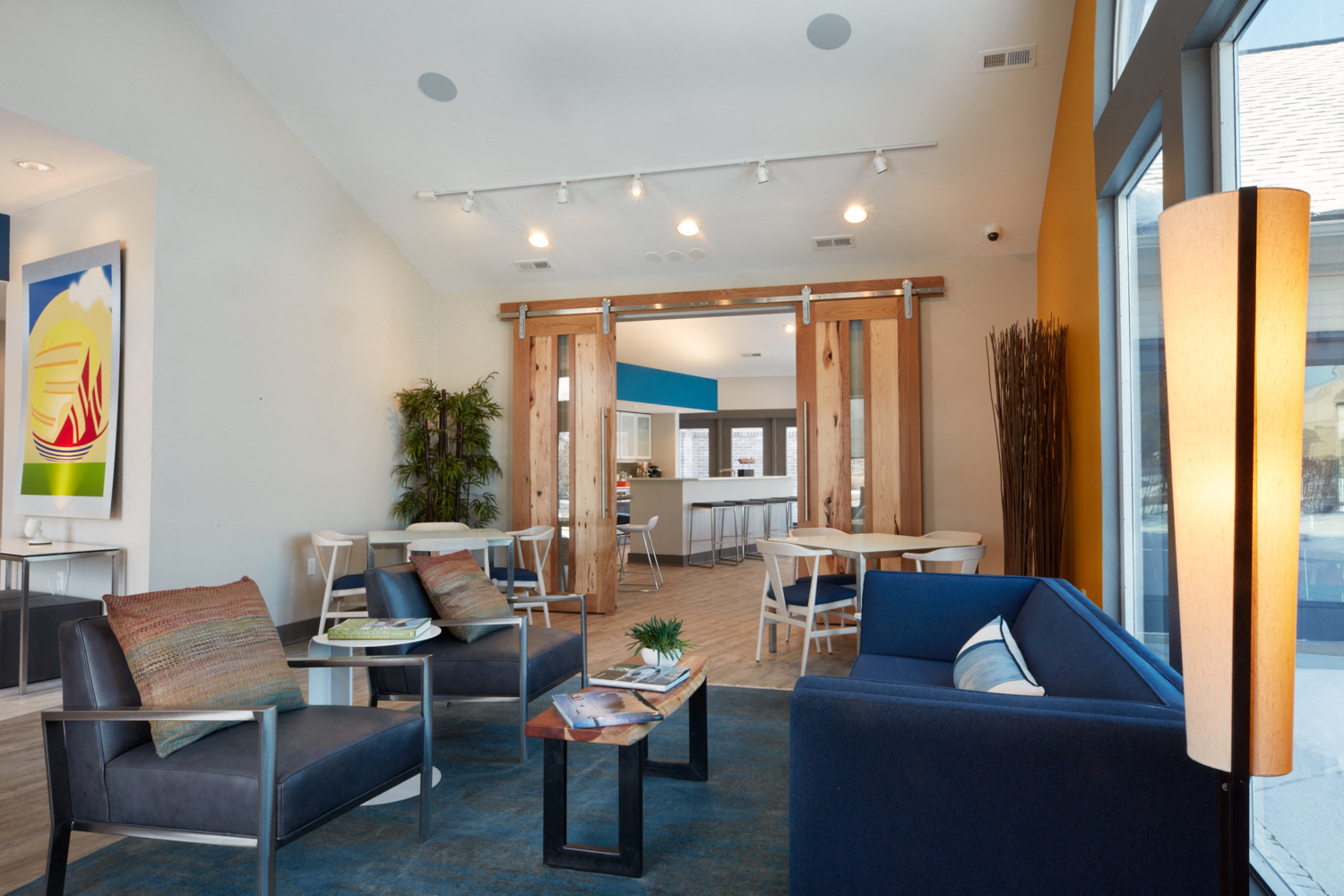 a living room with blue couches and chairs and a dining room with a kitchen