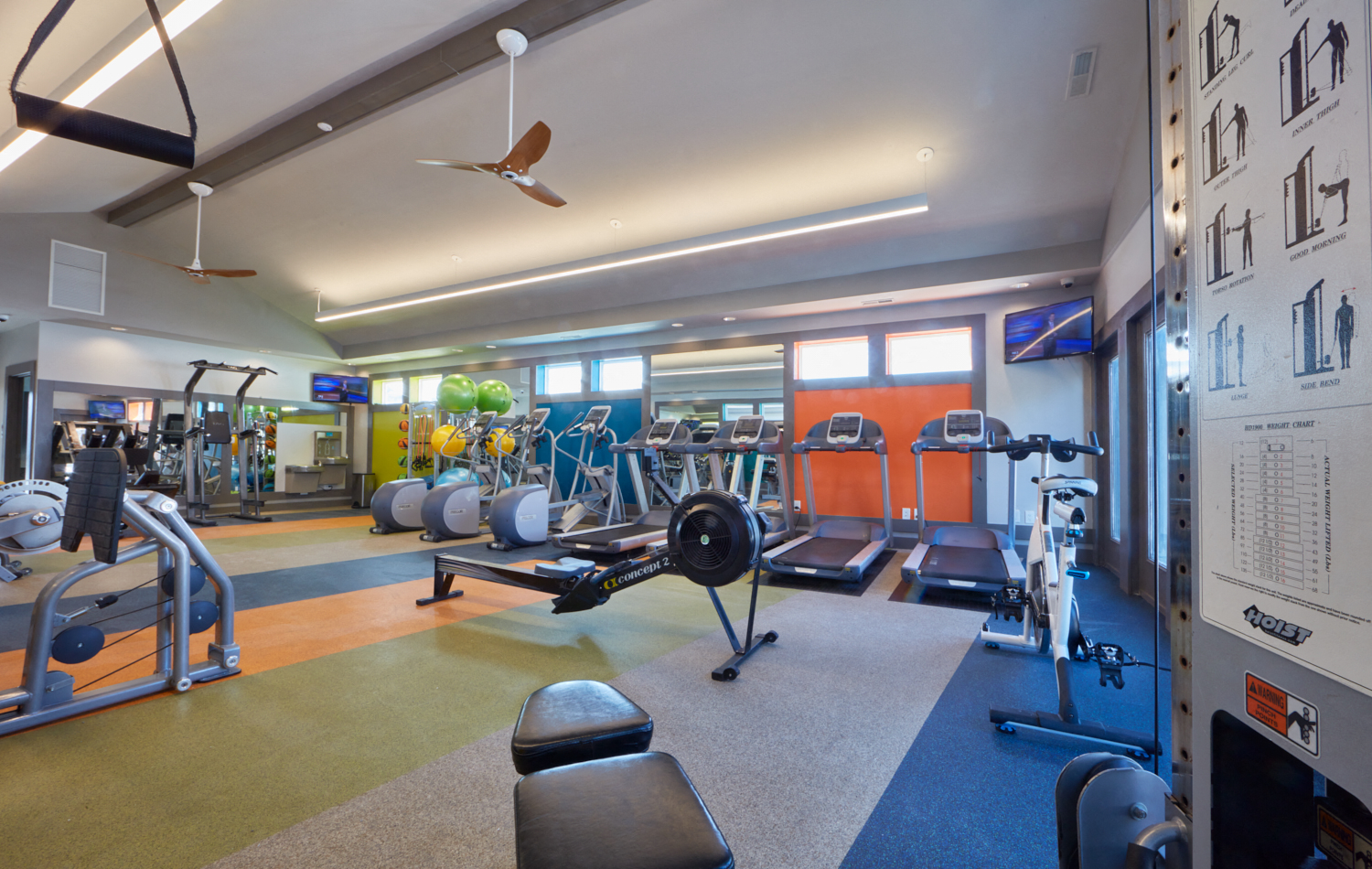 a gym with weights and cardio machines and a ceiling fan