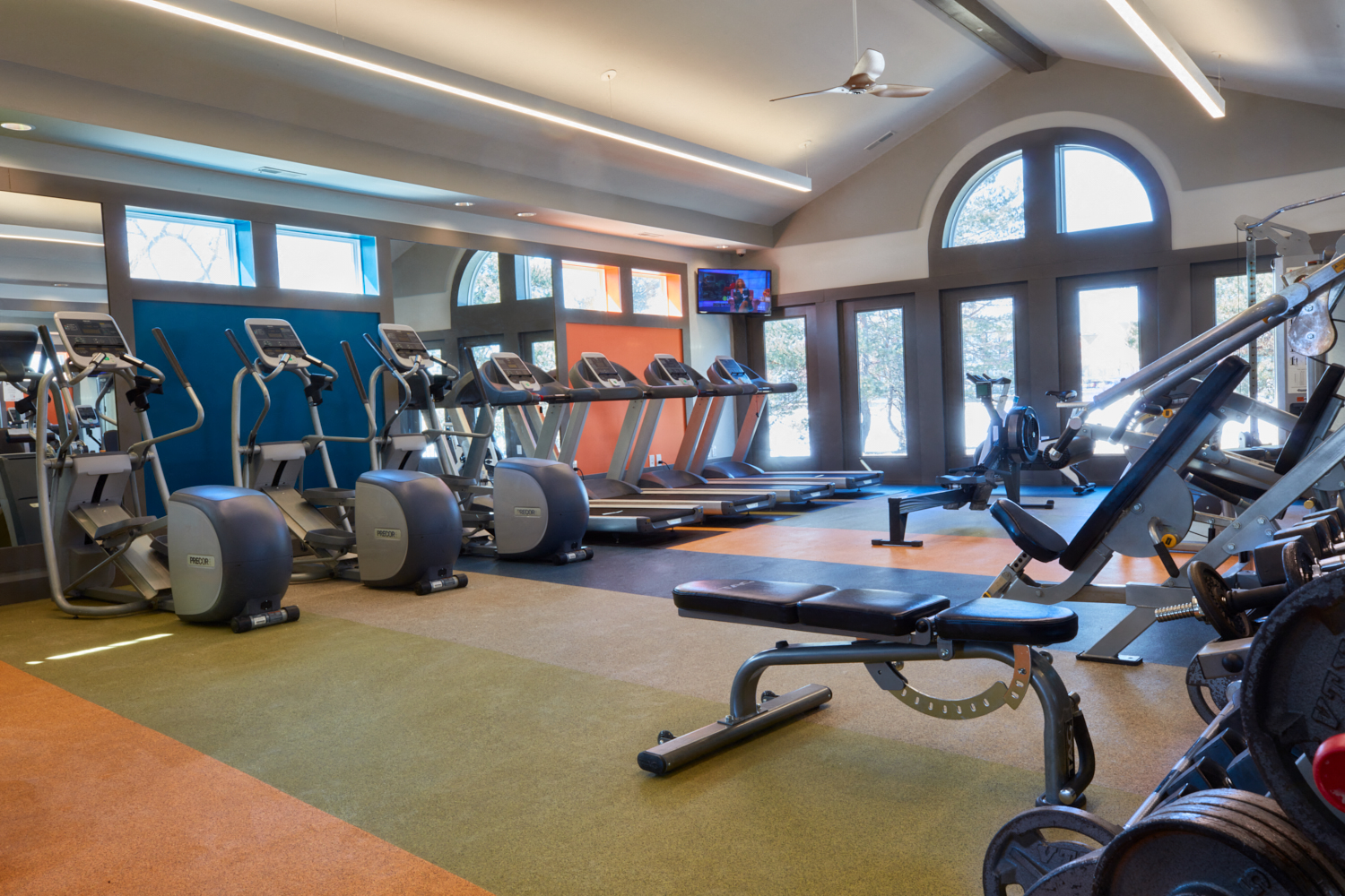 a gym with cardio equipment and windows in a building