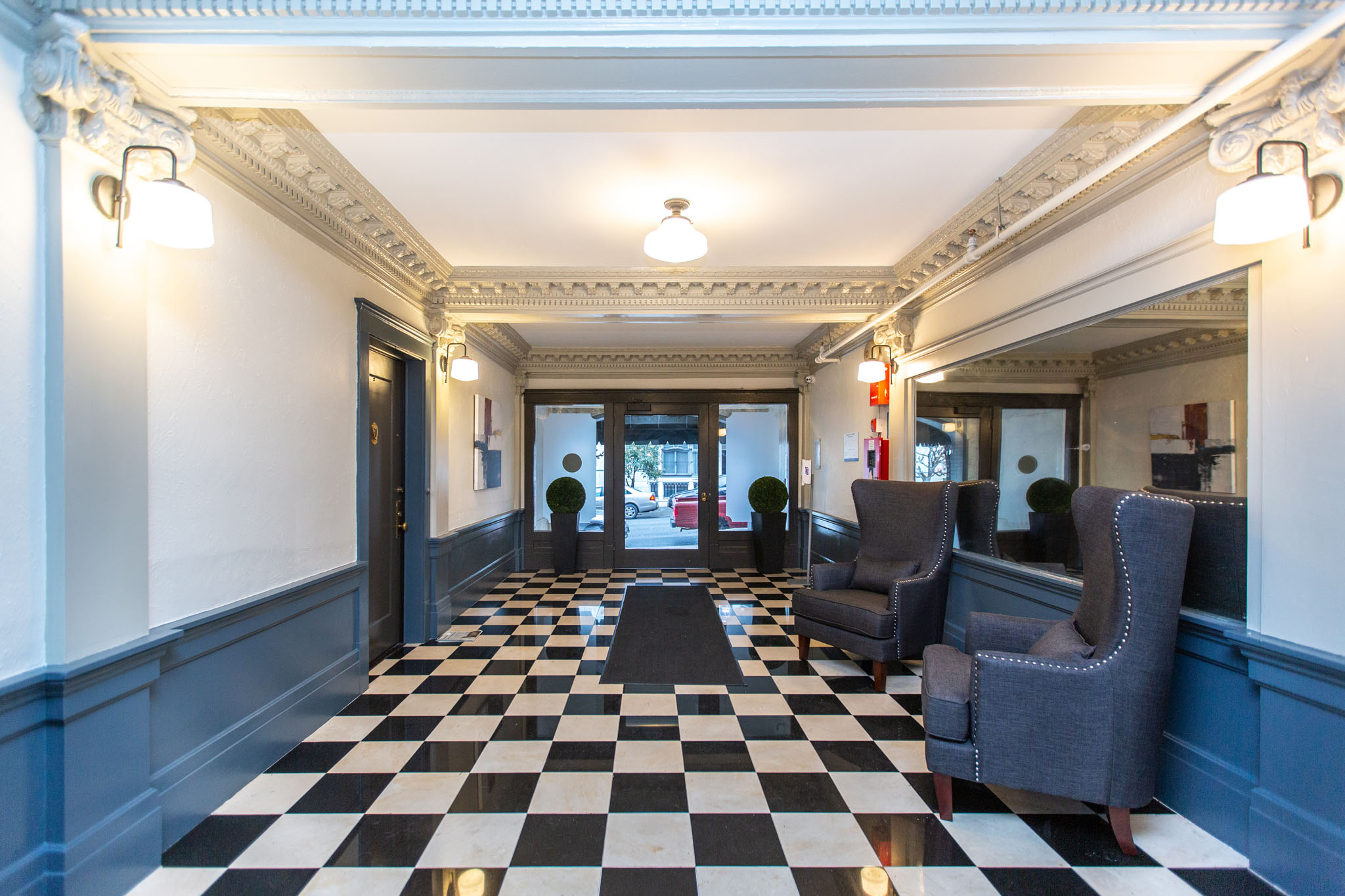 A black and white checkered floor in a room with grey chairs.