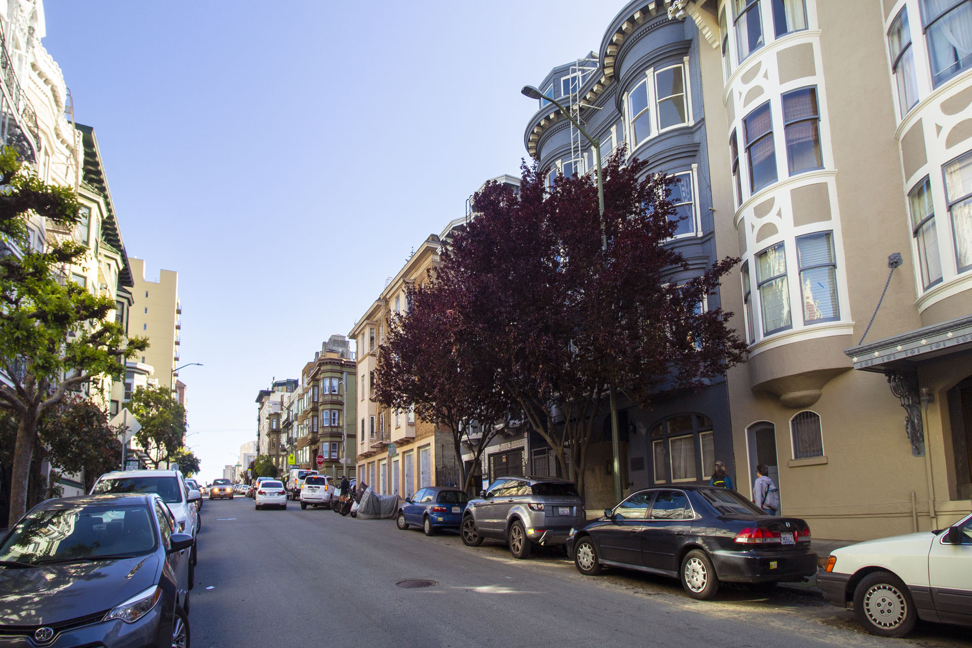 A street with cars parked on both sides and buildings on the side.