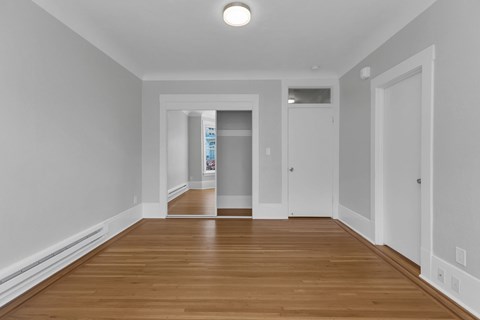 A long, empty hallway with wood floors and white walls.