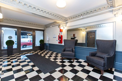 A black and white checkered floor in a room with two chairs and a fire extinguisher.