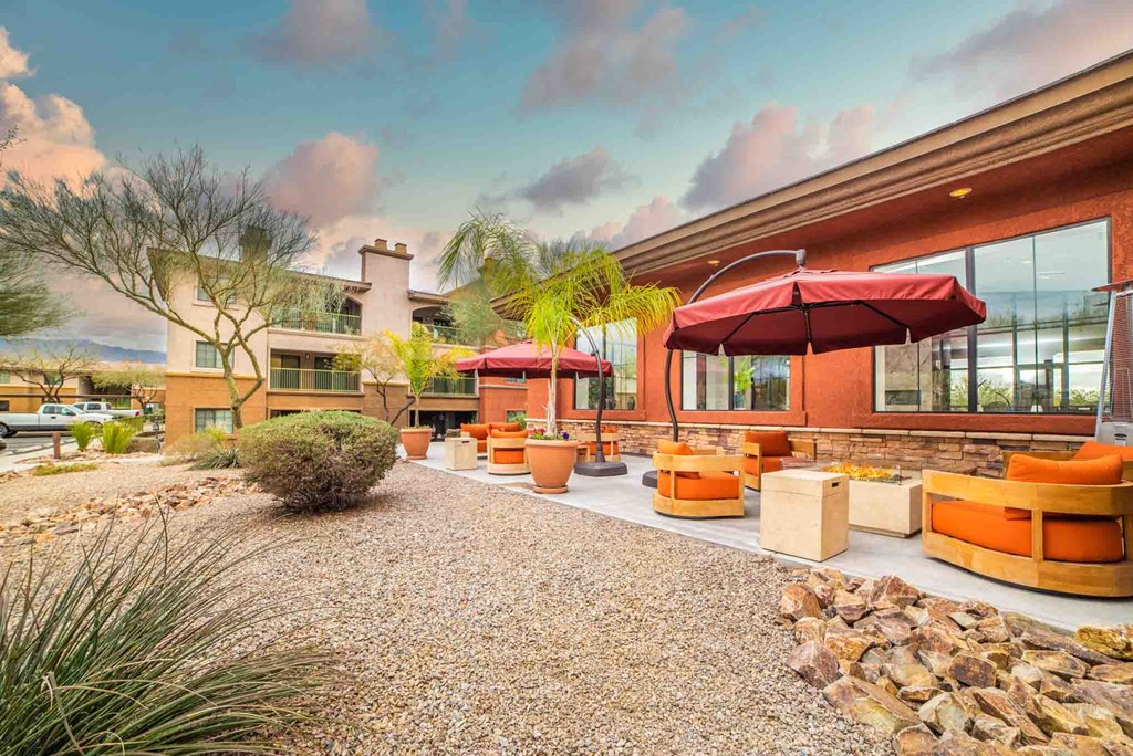 a patio with couches and umbrellas in front of a house