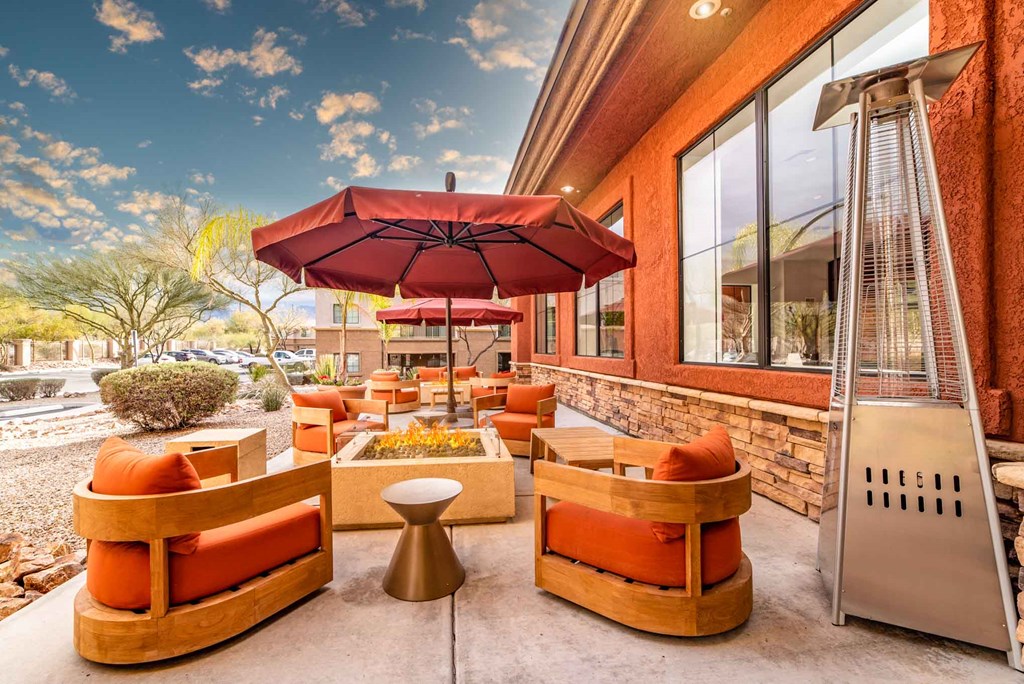 a patio with couches and umbrellas outside of a building
