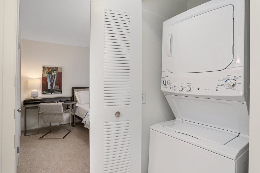 a washer and dryer in a closet next to a room with a bed