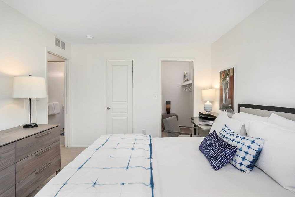 a bedroom with a white bed and a desk with a chair