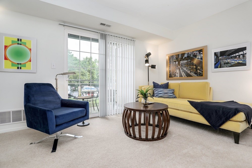 a living room with a couch and a chair and a door to a balcony